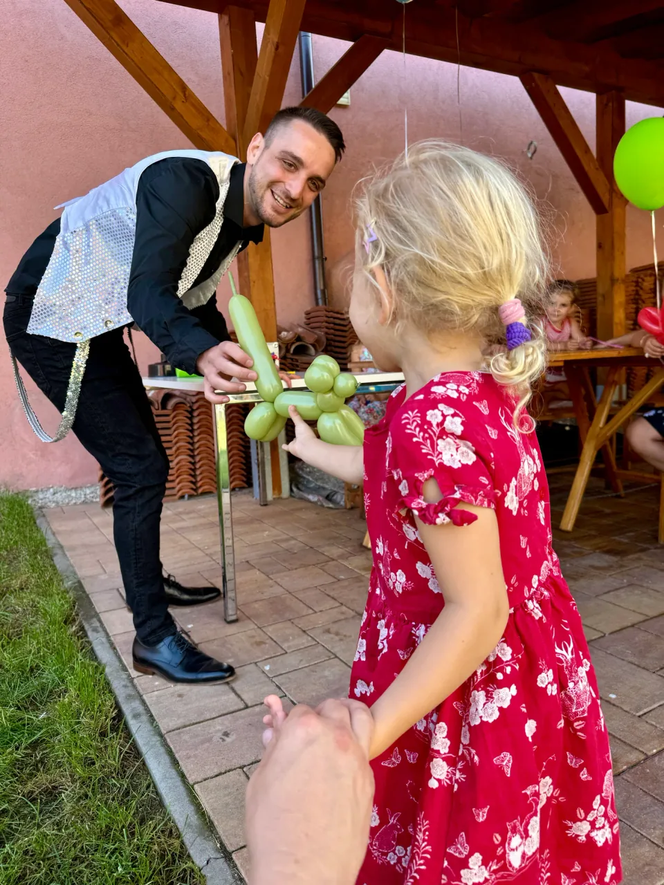 Robin předává dítěti zeleného balónkového pejska
